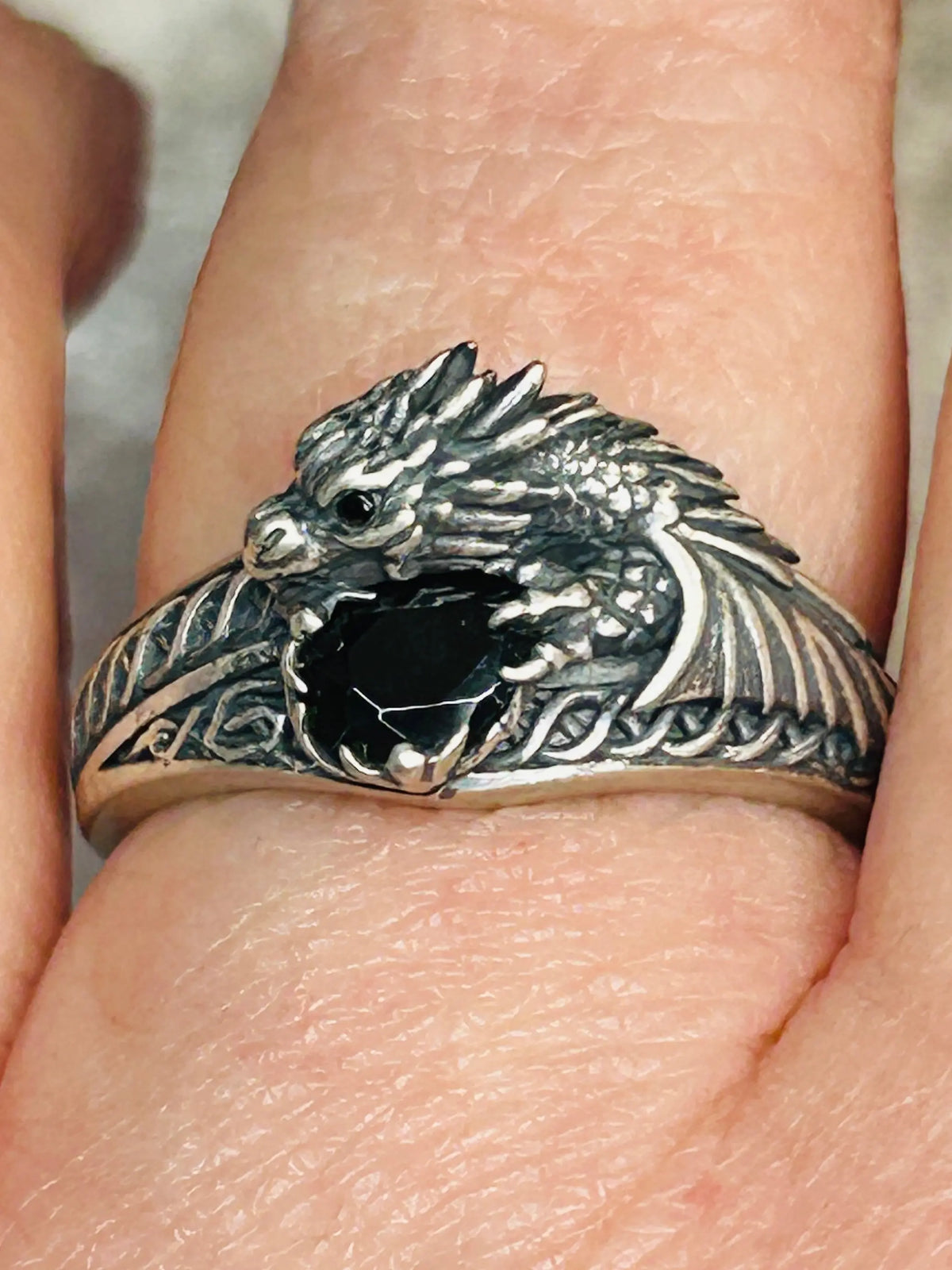 Silver dragon ring with black stone on a finger