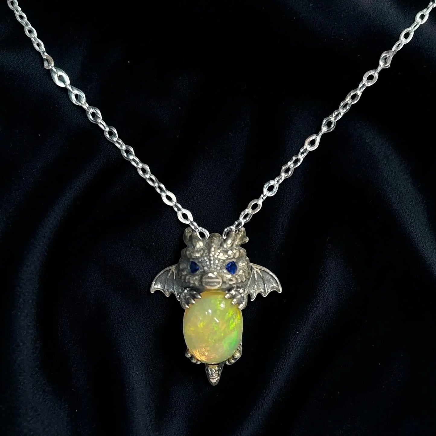 Celtic Dragon Jewellery baby dragon pendant with blue cz eyes holding a vibrant opal gemstone, made of 925 sterling silver.
