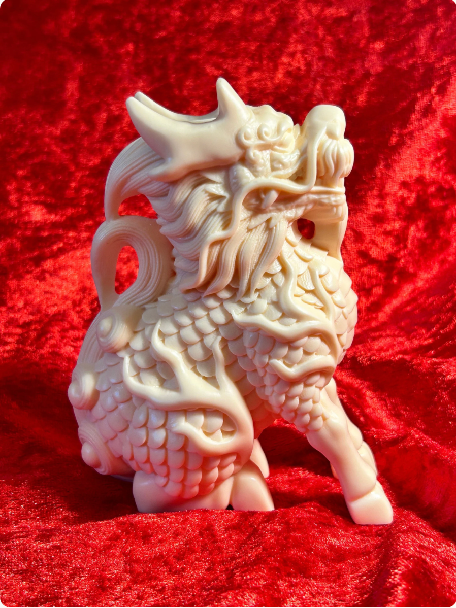Side view of a 5-inch cream-coloured Chinese dragon figurine made from ivory nut composite, featuring ornate horns, flowing whiskers, detailed scaled and curled tail against red velvet.