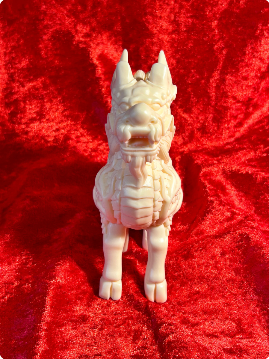 Front view of a 5-inch cream-coloured Chinese dragon figurine made from ivory nut composite, showing its open mouth, prominent horns, detailed facial features and scaled chest against red velvet.