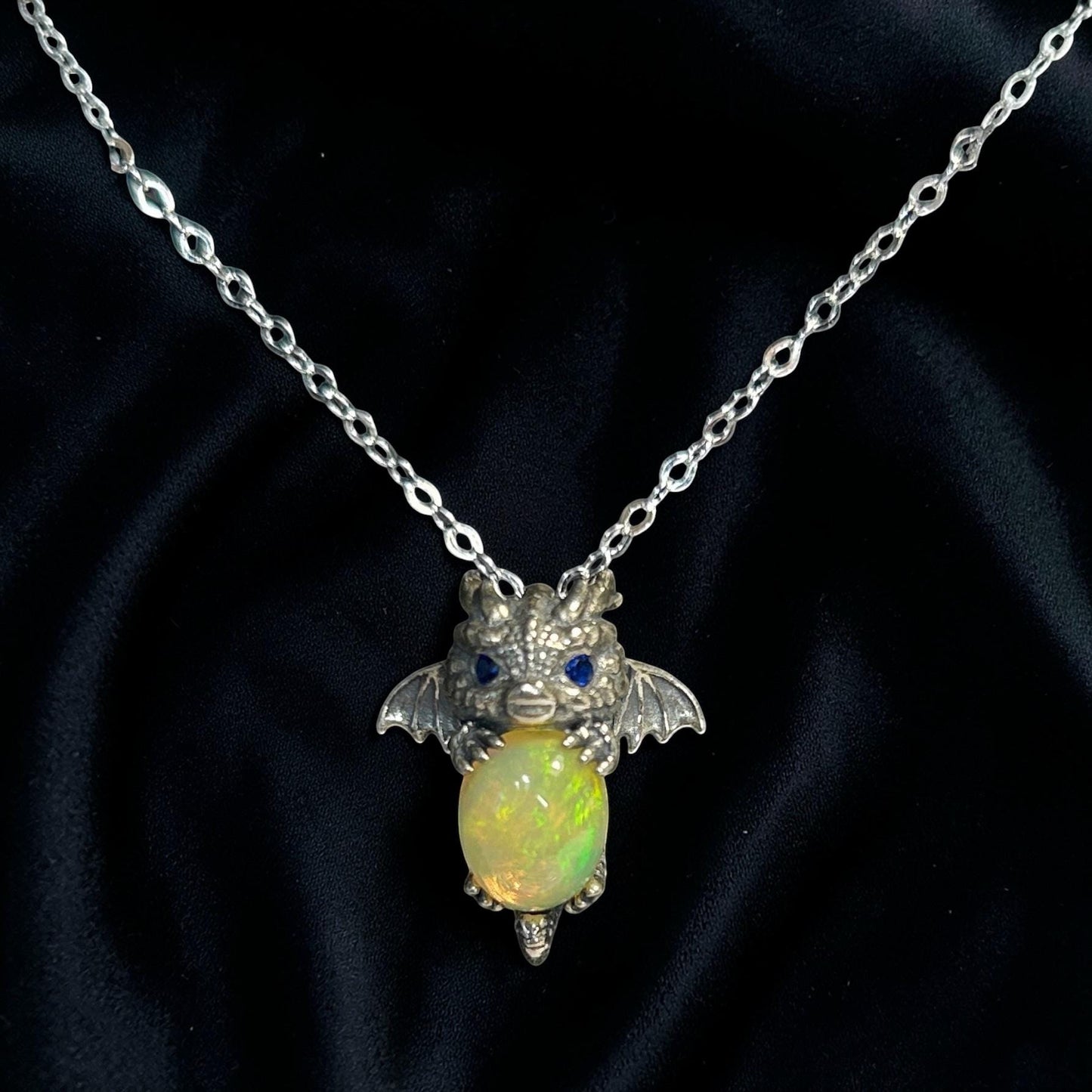 Celtic Dragon Jewellery baby dragon pendant with blue cz eyes holding a vibrant opal gemstone, made of 925 sterling silver.