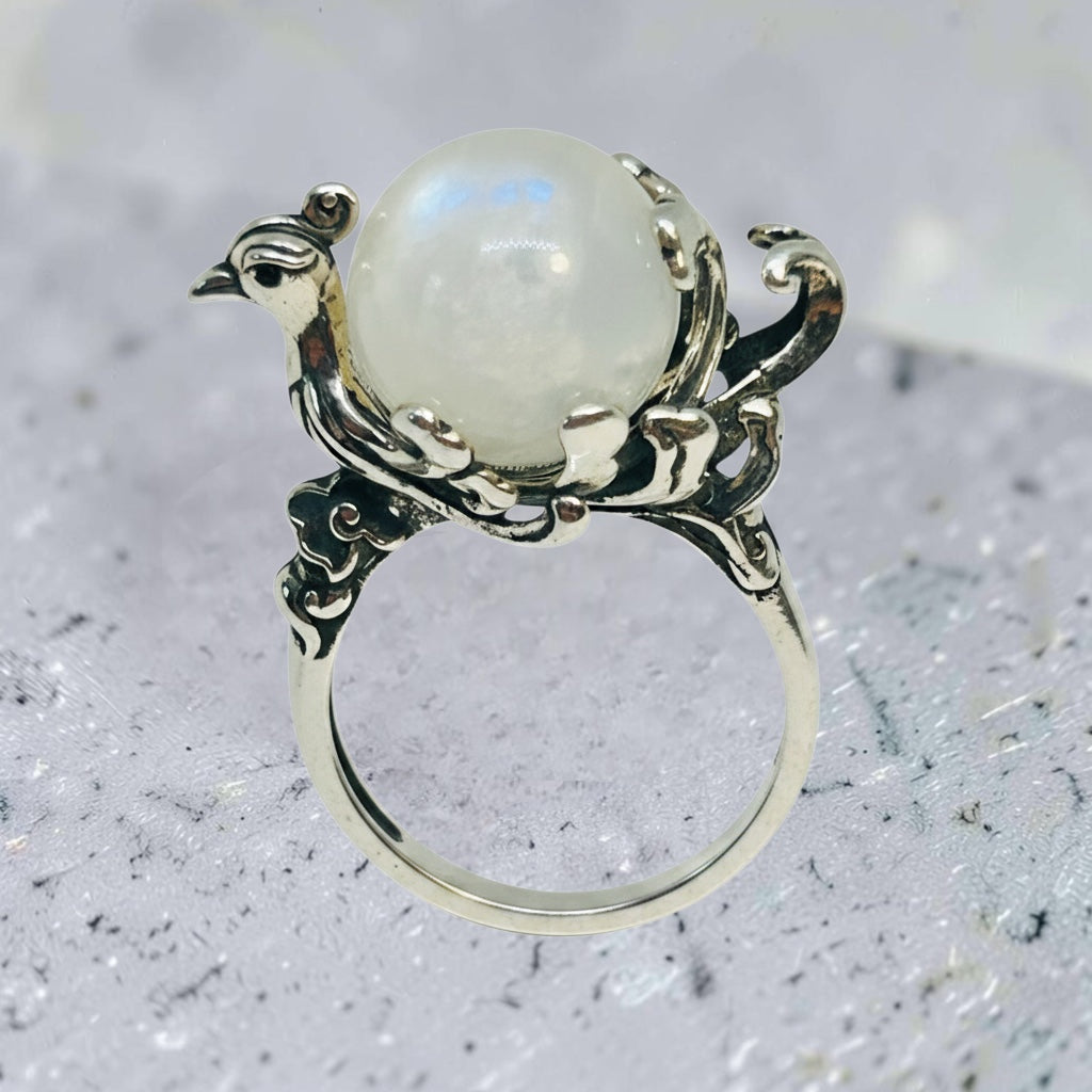 Celtic Dragon Jewellery adjustable sterling silver ring featuring a detailed phoenix holding a prong-set rainbow moonstone sphere.