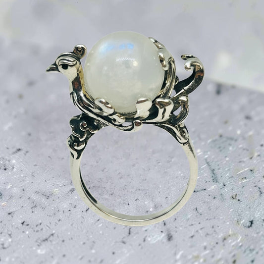 Celtic Dragon Jewellery adjustable sterling silver ring featuring a detailed phoenix holding a prong-set rainbow moonstone sphere.